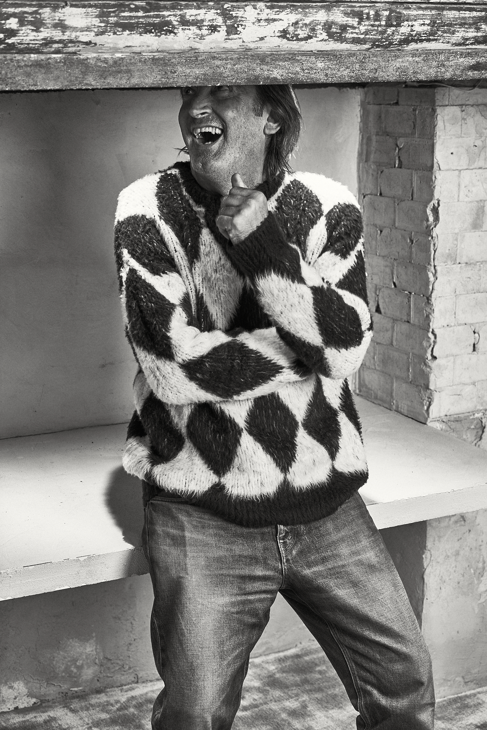 Uomo in maglione seduto che ride. Beppe Angiolini. Ritratto di Gianluigi Di Napoli